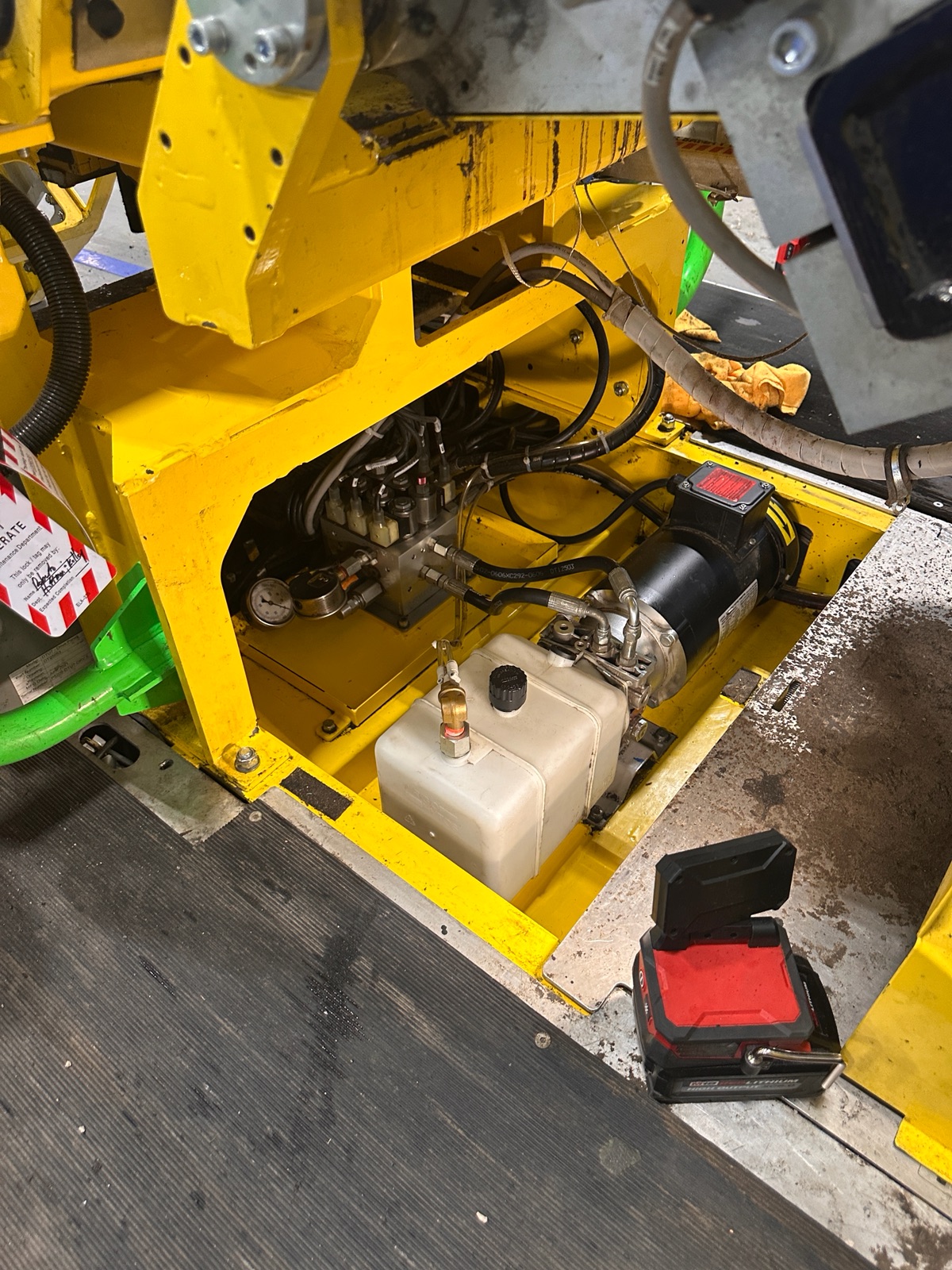 Opened Destuff-It hydraulic power unit with motor, reservoir, valve manifold, gauge, and lockout-tagout tag